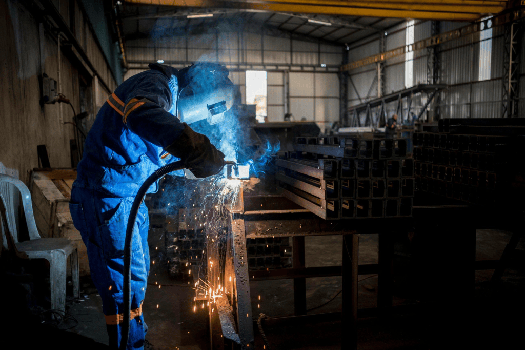 Welder fabricating stainless steel components in a metal workshop for custom project production.