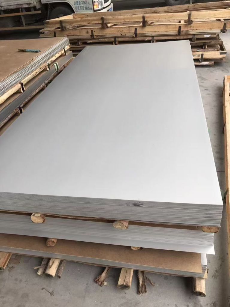 Large stainless steel sheets stacked on a pallet, showing flat sheet material available in different thicknesses, widths and surface finishes.
