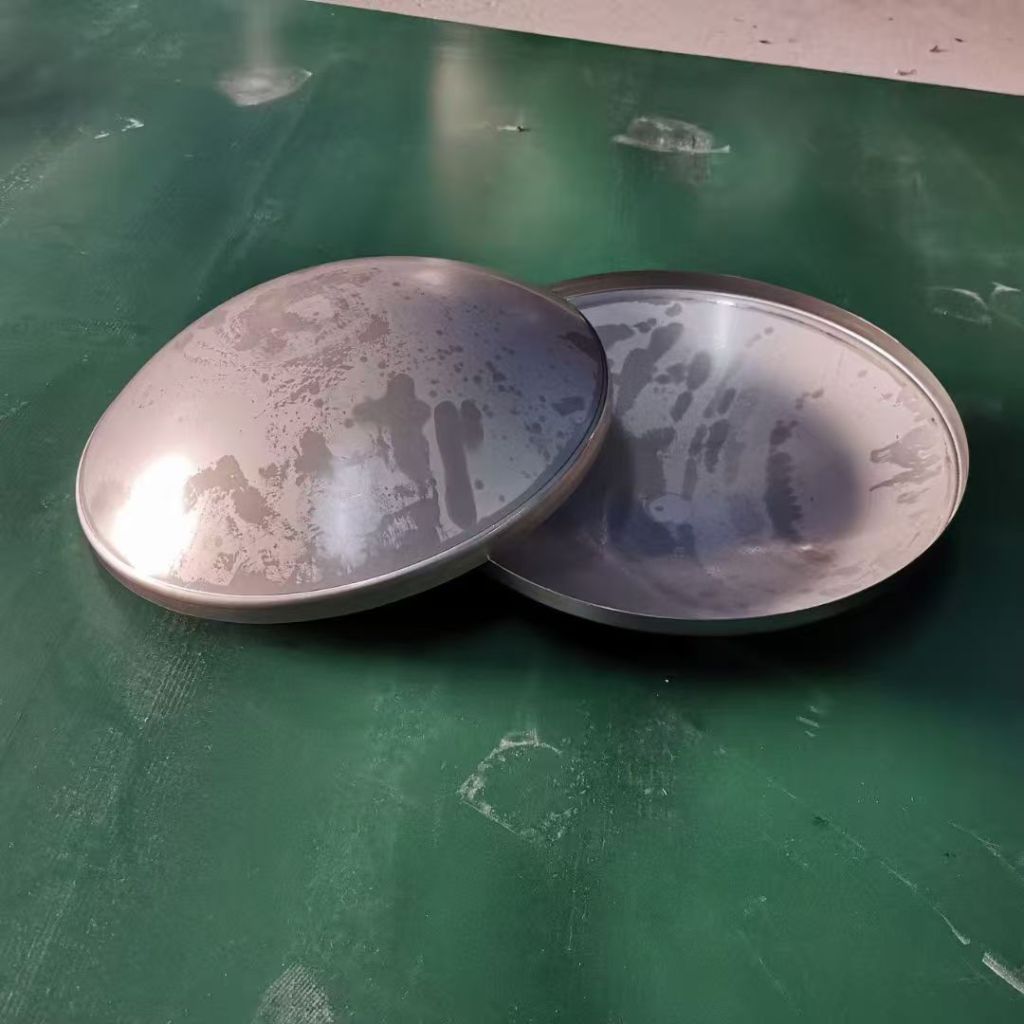 Two stainless steel dished heads showing their circular shape and curved formed surfaces for custom vessel fabrication.