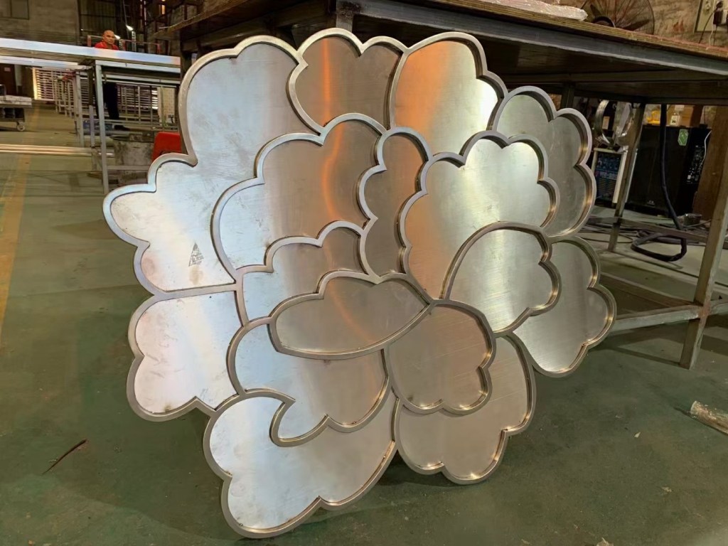 Custom decorative stainless steel inlay with layered floral shapes and metallic finishes, fabricated for interior wall features, decorative panels and architectural metalwork.