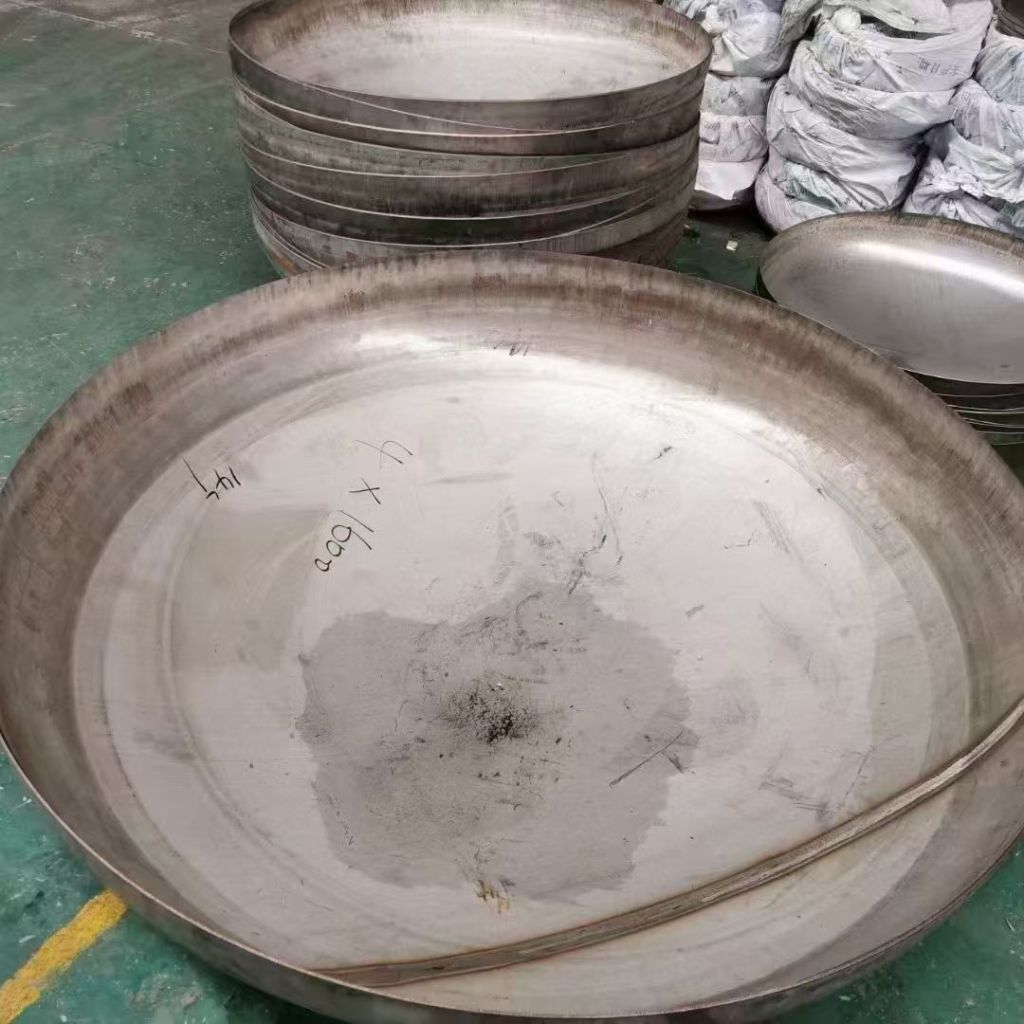 Large stainless steel elliptical head showing its circular diameter, formed edge and shallow curved surface for custom pressure vessel applications.