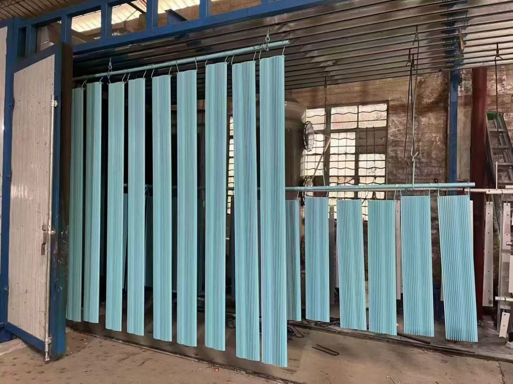 Light blue powder-coated metal profiles hanging in coating workshop