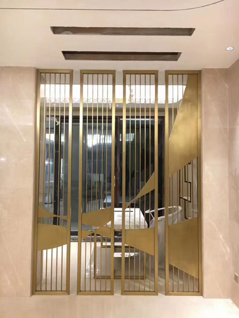 Custom stainless steel screen and partition with vertical decorative metal profiles installed in a modern interior architectural space.