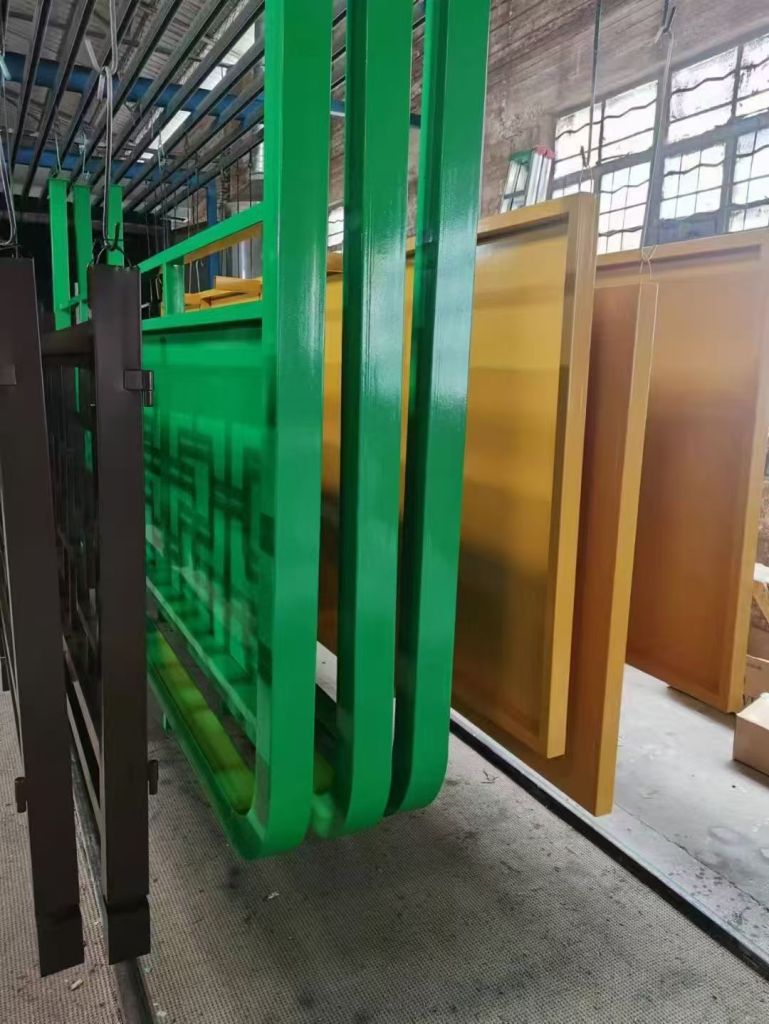Green and gold powder-coated fabricated metal components in workshop