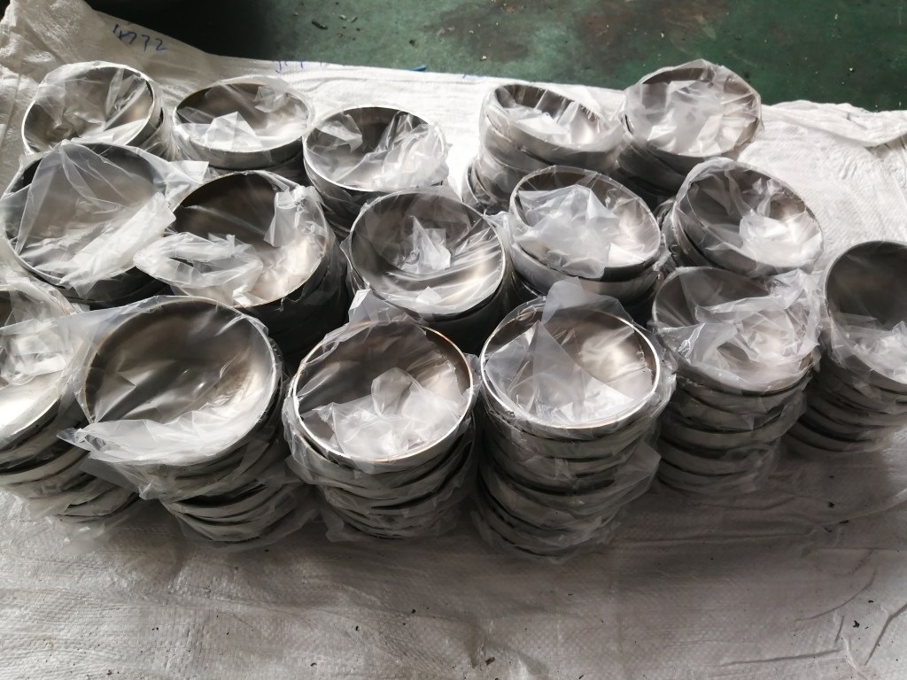 Custom stainless steel pressure vessel heads stacked in batches, showing formed metal heads manufactured for custom vessel and tank project requirements.