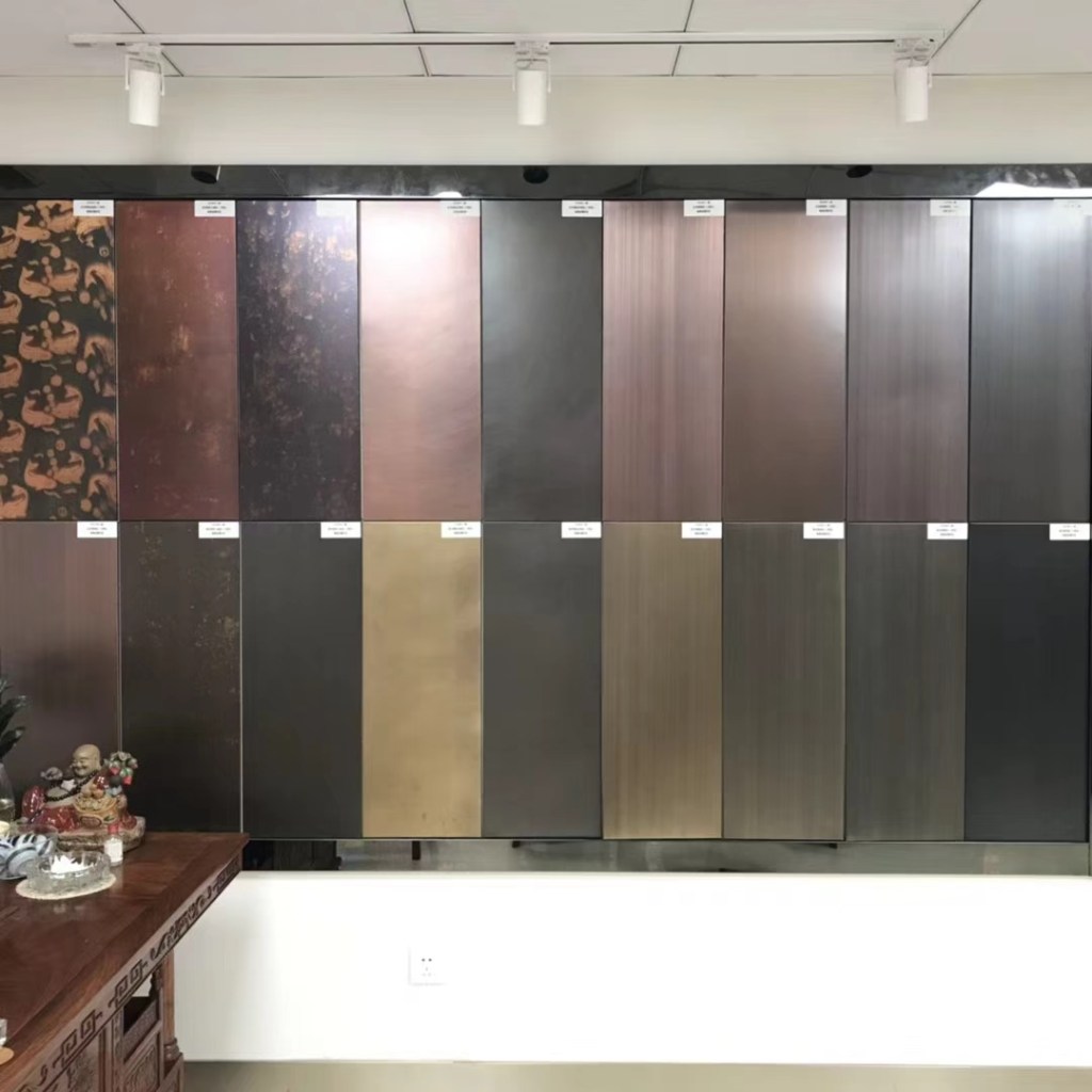 Display of stainless steel surface finish samples in silver, bronze, copper, gold and dark metallic tones, featuring brushed, mottled, textured and decorative patterns for custom stainless steel surface finishing.